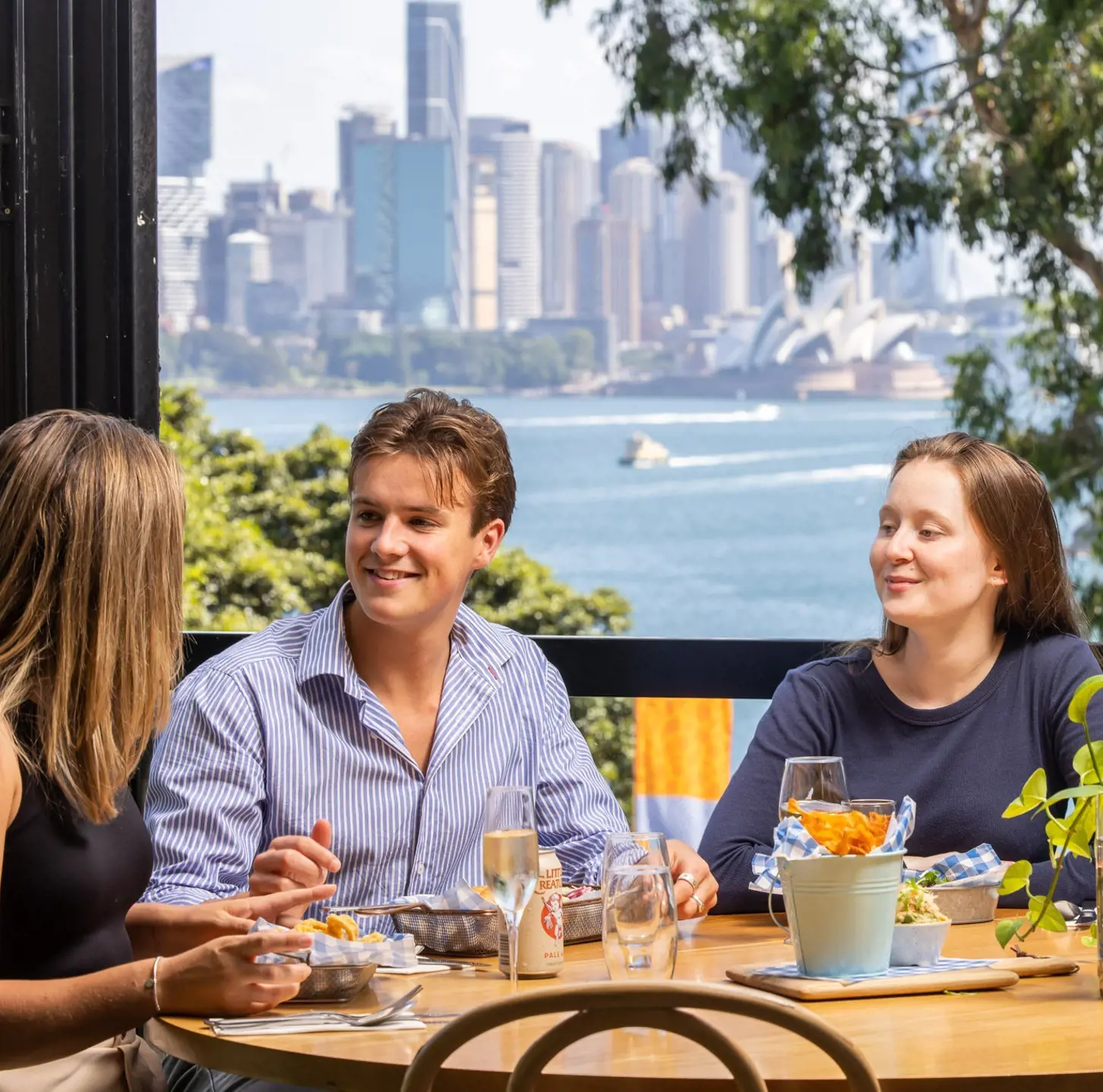 Guests dining at Saltwater Bistro with views across Sydney Harbour to the Opera House.