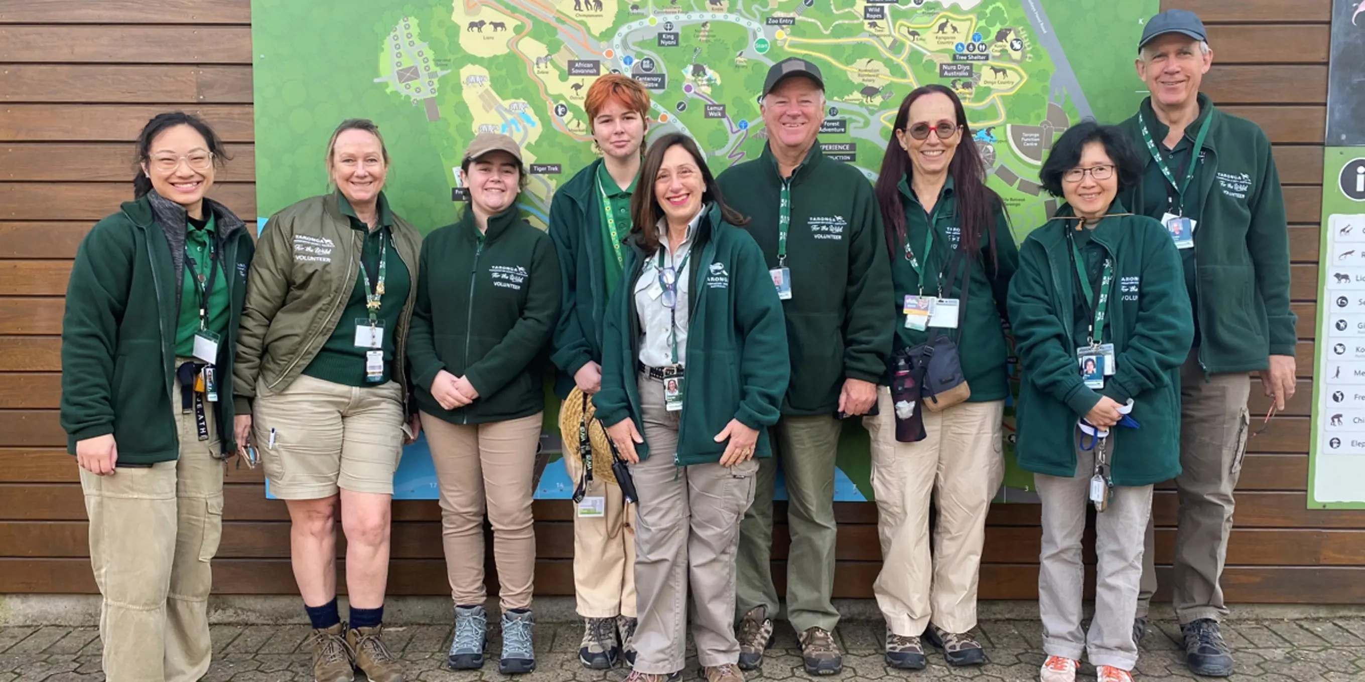 A group of Guest Experience Volunteers standing in front of the zoo map